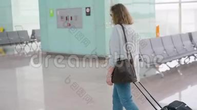 机场里的一个金发女郎带着滚动的<strong>行李箱</strong>包走路